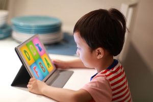 A child sitting in front of a tablet, enjoying screen time