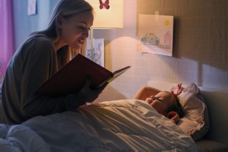 Bedtime Stories: Mother reading a storybook to her daughter before bedtime.- Babyhub