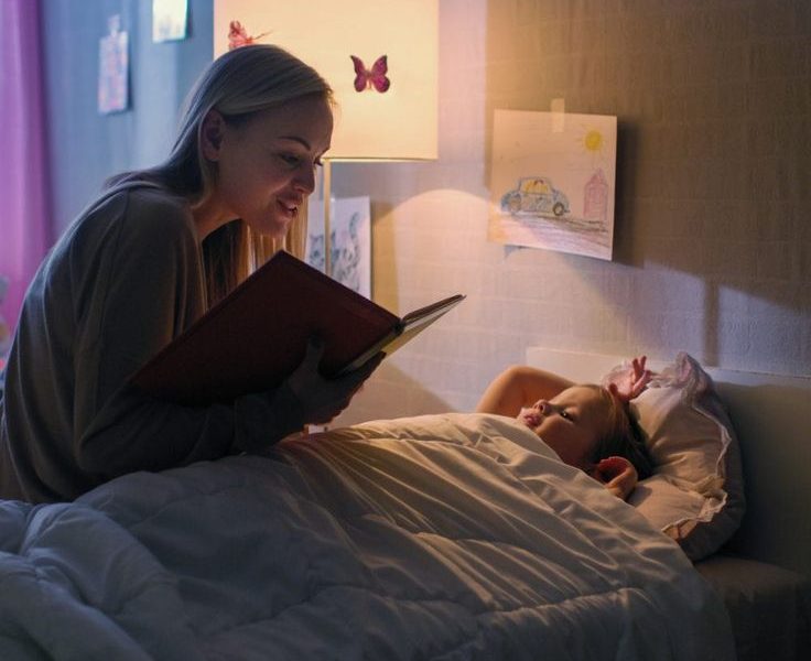 Bedtime Stories: Mother reading a storybook to her daughter before bedtime.- Babyhub