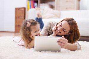  Mother and daughter enjoying screen time together, watching cartoons on a tablet.