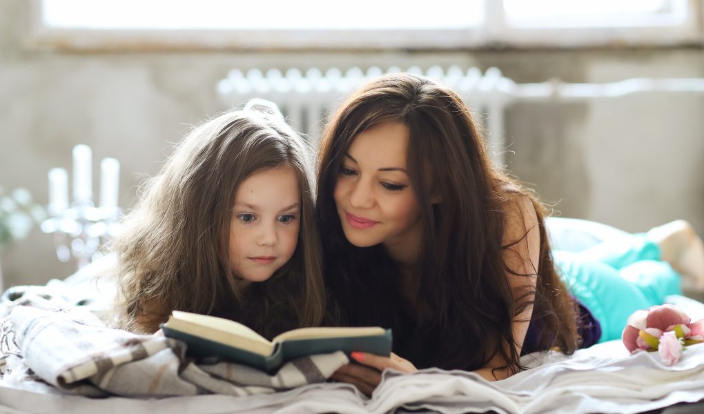 Bedtime Stories - Mother reading bedtime story with child snuggled beside her- Babyhub