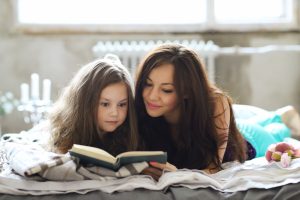 Bedtime Stories - Mother reading bedtime story with child snuggled beside her- Babyhub