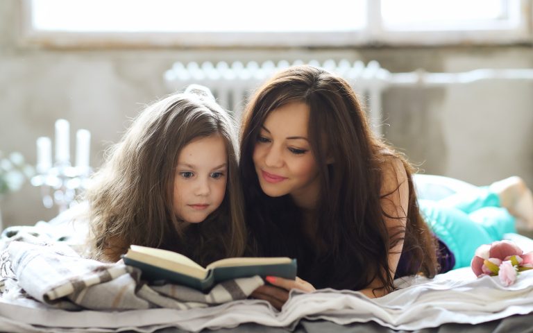 Bedtime Stories - Mother reading bedtime story with child snuggled beside her- Babyhub