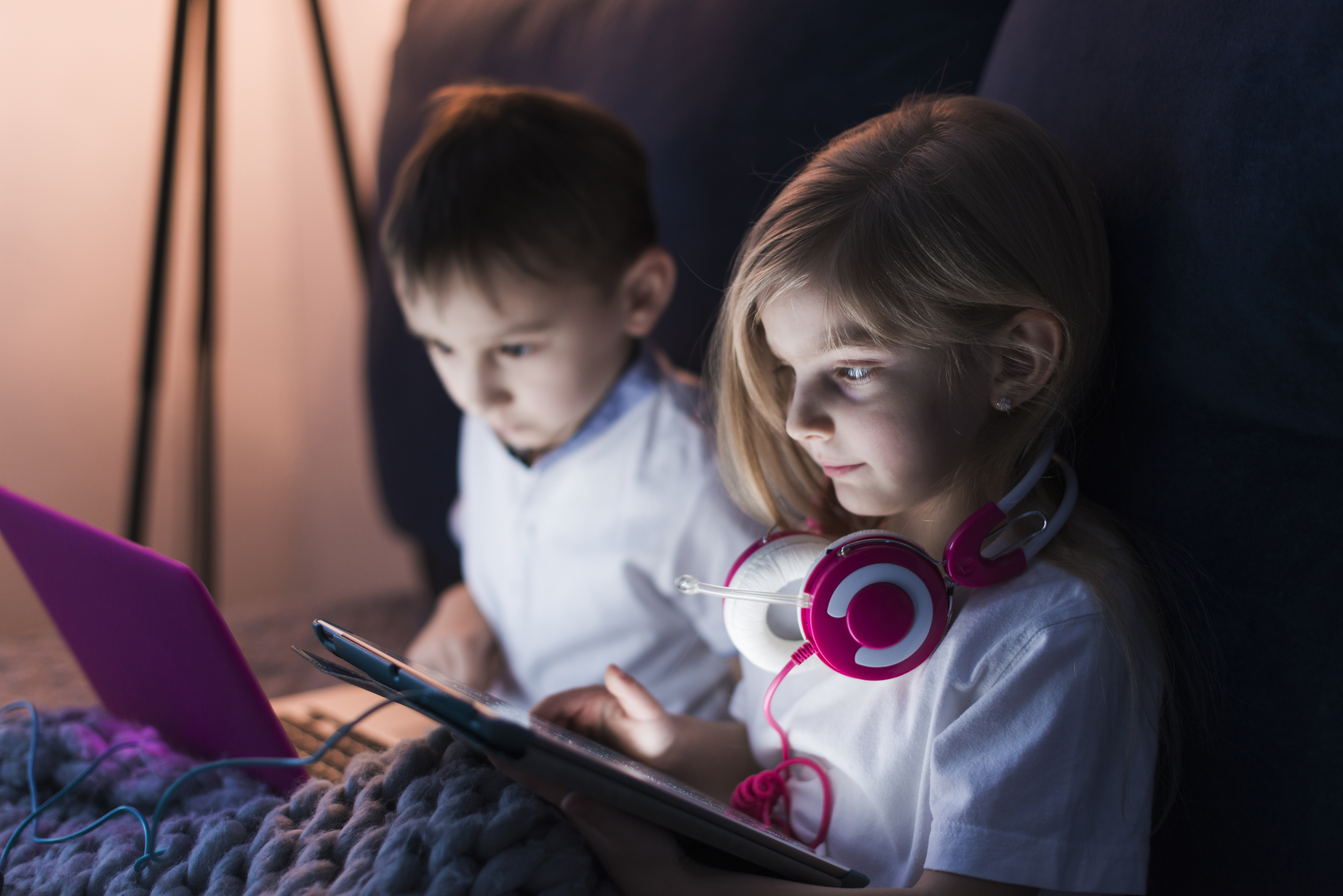 Kids engaged in screen time, each focused on their electronic device.