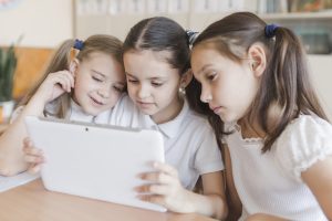 Screen time: Girls are happily engaged in activities on a tablet - Babyhub